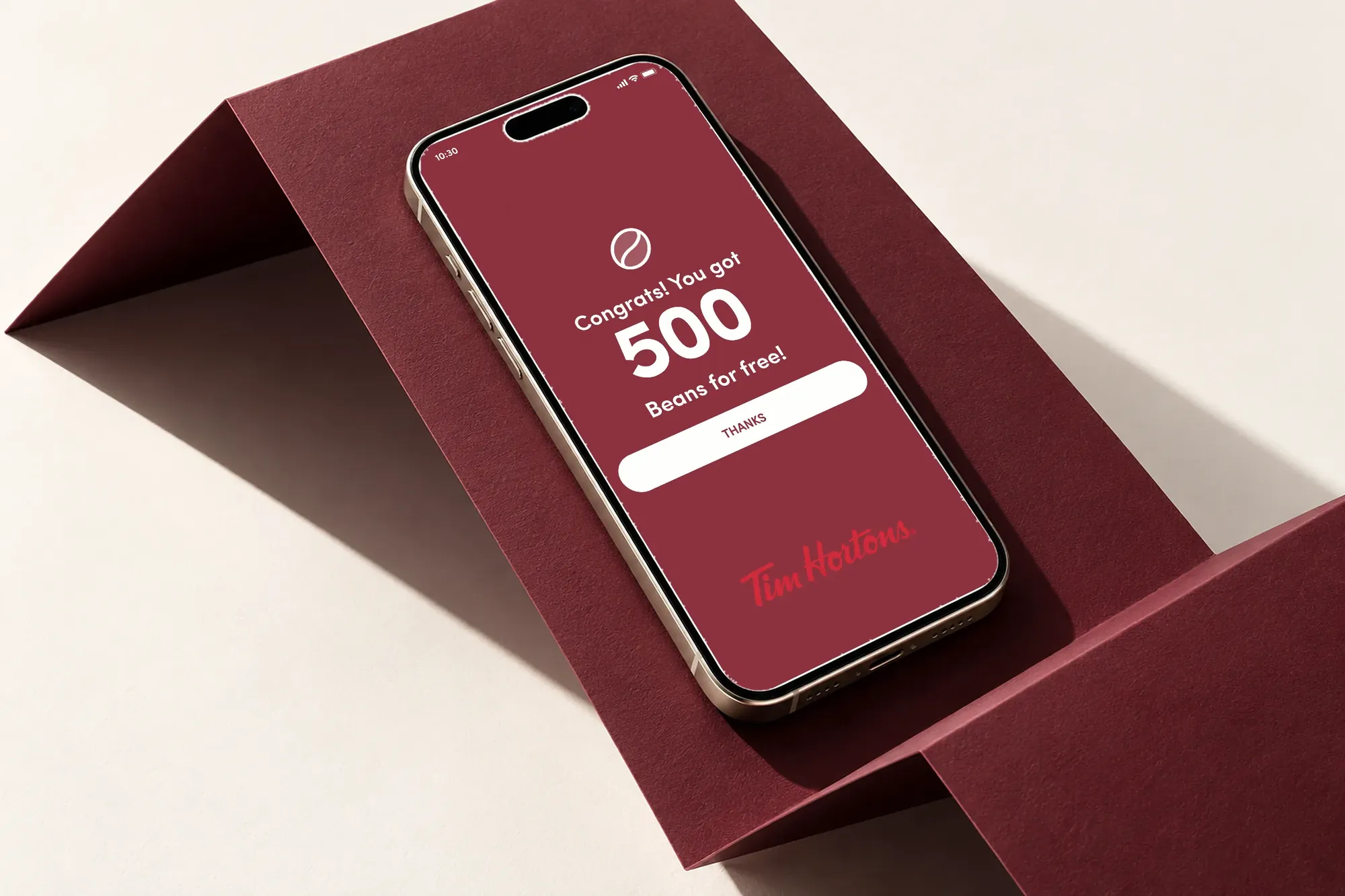 Tim Hortons 500 Beans reward screen on a phone resting on folded maroon paper